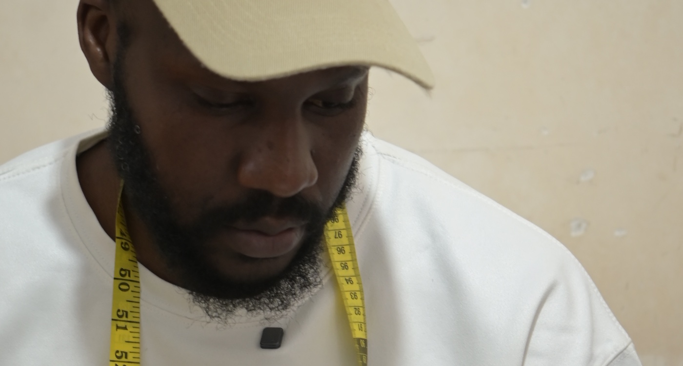 Un tailleur, mètre ruban autour du cou, le regard baissé sur son ouvrage